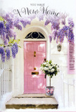 A tranquil Lea Bridge homecoming is captured in this photograph of a pink front door dressed in soft, romantic florals. The door, painted a delicate pastel pink, stands at the centre of the scene, its colour glowing warmly against surrounding whitewashed walls that recall the light, open feel of homes near the River Lea. To one side, a matching pale shutter lends balance and reinforces the gentle, welcoming palette. Above the entrance, trailing boughs of wisteria spill down in layers of lavender and soft purple, forming airy floral curtains that frame the doorway. Each drooping cluster of blossoms suggests a subtle, sweet scent and a sense of movement, as though a light breeze from the Lea Bridge marshes has just stirred them. Sitting right at the threshold, a vintage-style grey bucket holds an abundant bouquet of white and cream roses. The roses are tightly packed and velvety, their rounded blooms unfolding in creamy spirals, laced with snippets of fresh green foliage that create a natural, relaxed elegance. A blush-pink satin ribbon is wrapped around the bucket and tied into a simple bow, its soft shine mirroring the door's gentle tone and linking the entire pastel scheme from top to bottom. The light in the scene is calm and diffused, casting soft shadows on the step and picking up texture in the petals, paint, and stone. The overall feeling is hopeful and intimate, as if this floral arrangement has just been delivered to welcome someone to their new home in Lea Bridge, offering quiet congratulations, comfort, and a beautifully scented promise of new memories at this doorway.