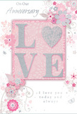 The image presents a romantic anniversary card whose delicate artwork seems to capture the quiet charm of Lea Bridge at dusk. At its centre rests the word "LOVE," printed in large, raised capitals that offer both visual impact and a subtle tactile experience. These letters are rendered in soft blush pink and creamy white, then kissed with a fine layer of shimmering glitter that adds a gentle silver sparkle along their contours. When touched, the glittery embossing would feel faintly rough against the smooth card, inviting a moment of lingering contact. Encircling this central word, elegant illustrations of flowers and leaves drift across a powdered pink background, reminiscent of petals floating down near the River Lea after a spring breeze. The blossoms are stylized yet graceful, sketched in thin grey lines and softly shaded in blush, ivory, and pale silver, mirroring the thoughtful balance a florist from Florist Lea Bridge might create in an anniversary bouquet destined for a home by Millfields Park. The stems curl and spiral around the lettering, their flowing curves adding movement without disturbing the card's gentle atmosphere. Among these botanical lines, delicate calligraphic script delivers heartfelt anniversary sentiments, its slim, looping forms evoking a personal note written with care. The design's overall palette remains understated-pastel pinks, pearly whites, and soft greys working together in quiet harmony. The effect is that of a tender celebration rendered in paper, a keepsake card that feels as lovingly composed as fresh flowers arranged for same-day delivery across Lea Bridge.